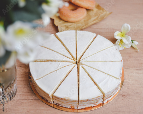 Fototapeta Naklejka Na Ścianę i Meble -  white cake with white flowers on wooden table and donuts on background