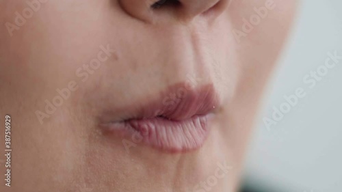 Roundfaced young woman eating French fries.A closeup shows her mouth, where she puts and eats French fries with pleasure. photo