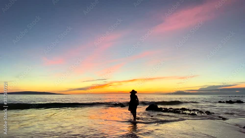 Silhouette of woman in dress and water against Hawaii sunset at beach Silhouette of woman in dress and water against Hawaii sunset at beach