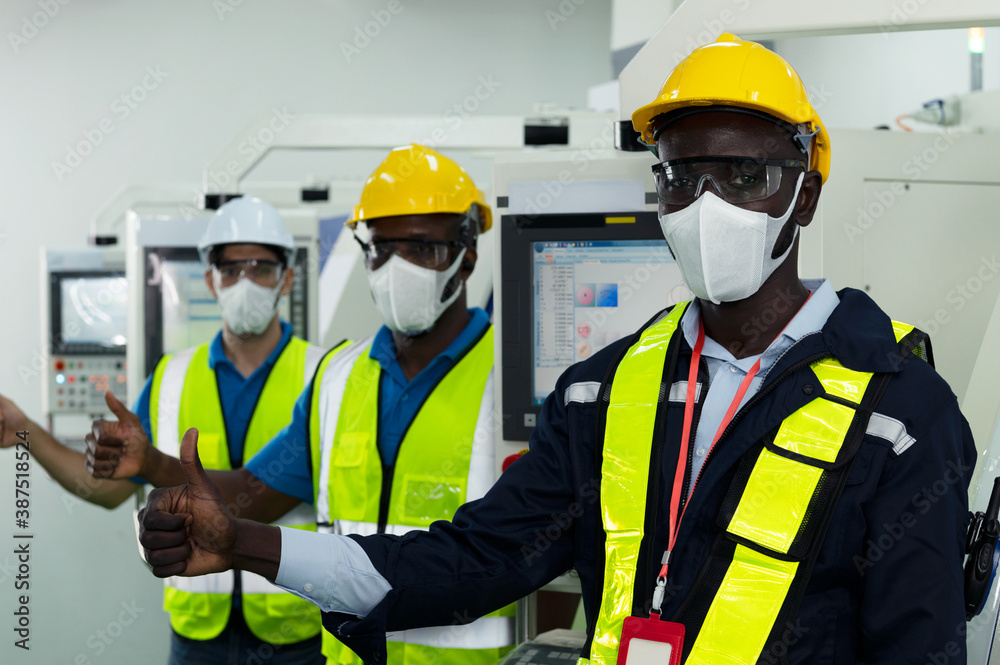 Group of diversity male factory technicians show confidence in factory with protective safety mask, glasses and helmet as new normal lifestyle during coronavirus or covid 19 outbreak Group of diversity male factory technicians show confidence in factory with protective safety mask, glasses and helmet as new normal lifestyle during coronavirus or covid 19 outbreak