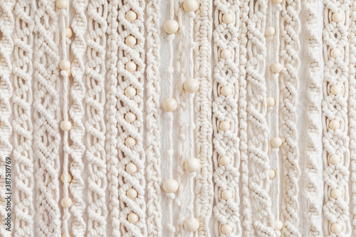Close-up of hand made macrame texture pattern. Eco friendly modern knitting. Natural decoration concept in the interior. Handmade macrame wall hanging 100% cotton and wooden beads