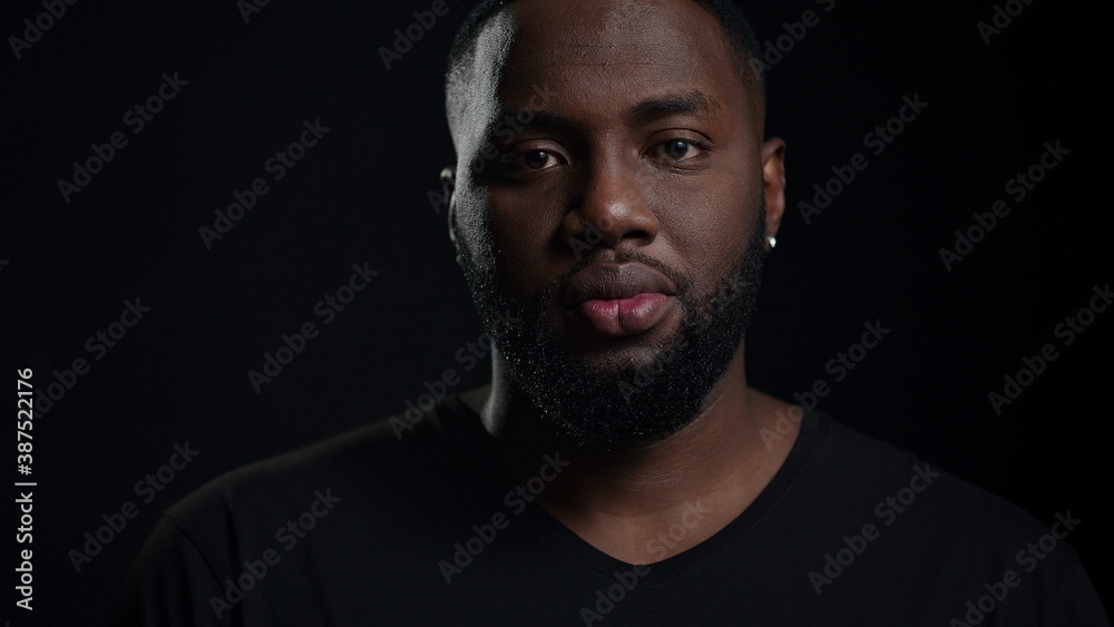 Relaxed afro guy looking at camera indoors. Smiling male person posing in studio Relaxed afro guy looking at camera indoors. Smiling male person posing in studio