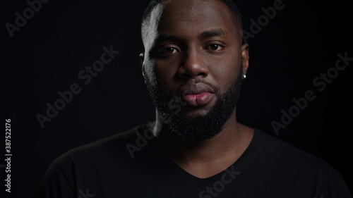 Relaxed afro guy looking at camera indoors. Smiling male person posing in studio © stockbusters