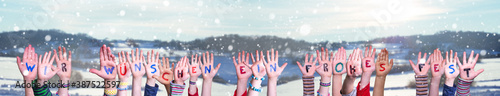 Children Hands Building Colorful German Word Wir Wuenschen Ein Frohes Fest Means We Wish You A Merry Christmas. Snowy Winter Background With Snowflakes