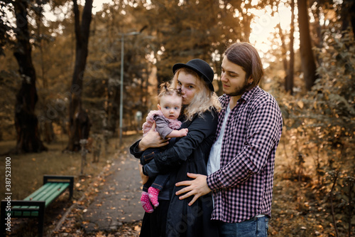  Father  mother and a 6 month old baby girl are posing in a fall park. Happy family concept