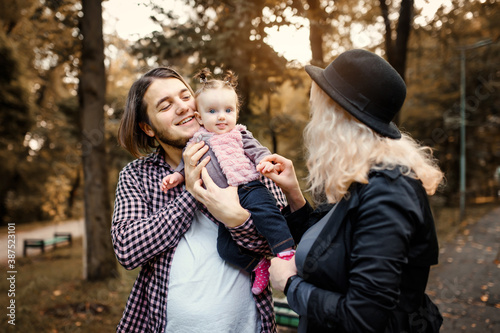 Father, mother and  6 month old baby girl are playing in a fall park.
