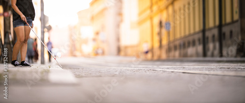 Fotografie Blind woman walking on city streets, using her white cane to navigate the urban