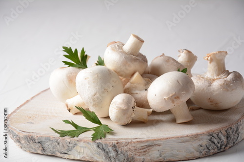 Fresh white champignon mushrooms on wooden board