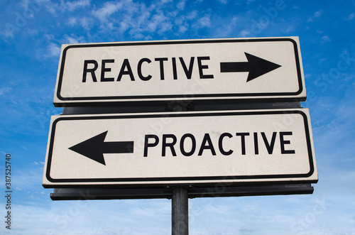 Reactive vs proactive. White two street signs with arrow on metal pole with word reactive and proactive. Directional road. Crossroads Road Sign, Two Arrow. Blue sky background.
