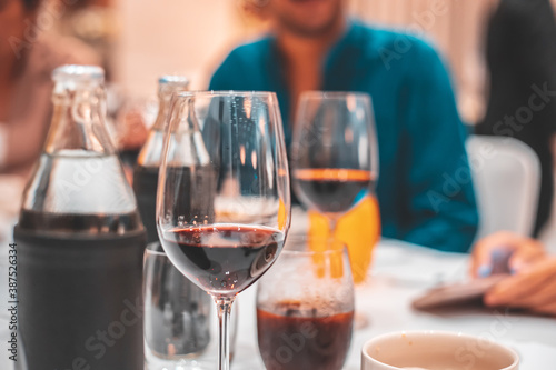 Glass of Red Wine on the food table with Lights Bokeh at night background.