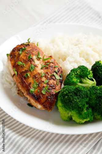 Homemade Chicken Breast, Rice and Broccoli on a white plate on a white wooden background, side view. Close-up.