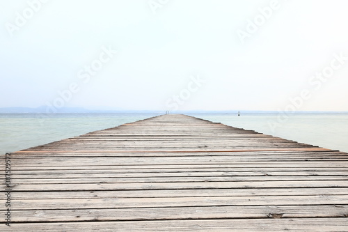Fototapeta Naklejka Na Ścianę i Meble -  The view along a wooden pier from the resort town of Sirmione on the banks of Lake Garda in north east Italy.