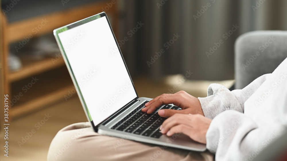 Cropped shot of young woman sitting on a couch in the living room at home and using laptop. Cropped shot of young woman sitting on a couch in the living room at home and using laptop.