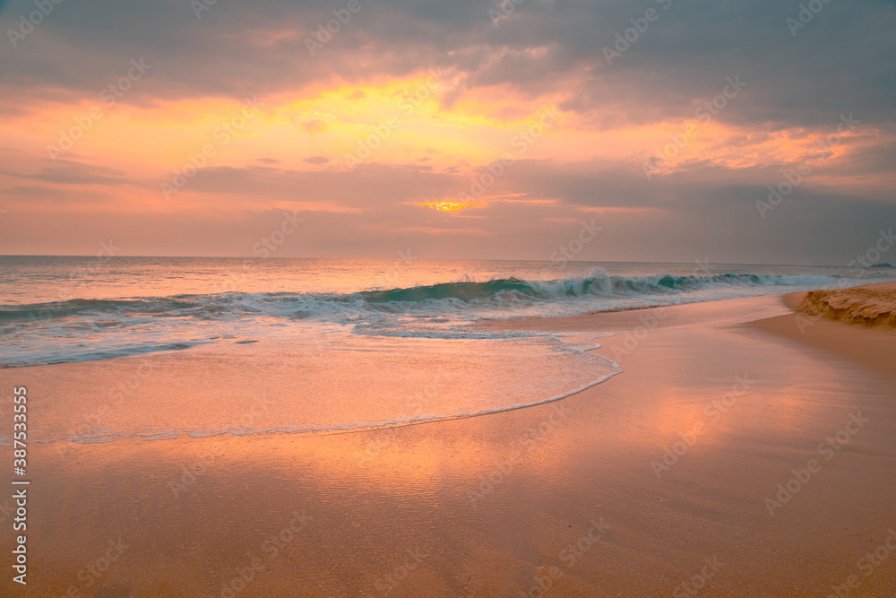 Obraz premium Beautiful ocean beach at sunset. Foamy waves over wheat sand and beautiful cloudy sky.