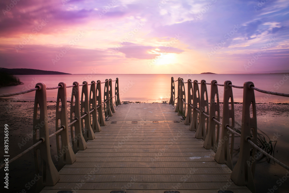 Sunset long exposure shot with plastic pier and cloudy purple and orange sky