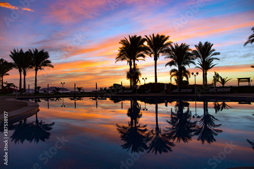 Beautiful bright sunrise reflected in the pool among palm trees over the Red Sea, Egypt