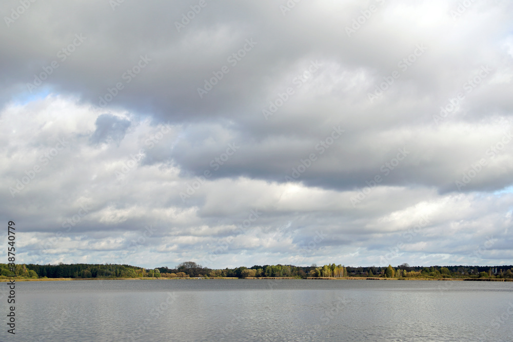 Autumn landscape. Beautiful white clouds in the blue sky above the lake. October. Day