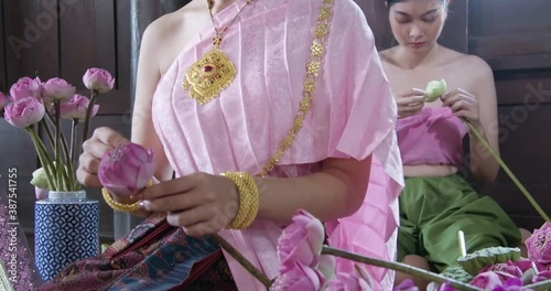 A beautiful asian female dress on Ayutthaya cultural fashion clothes sitting and flower decuration training traditional Thailand tomyam in the vintage old style ancient house photo