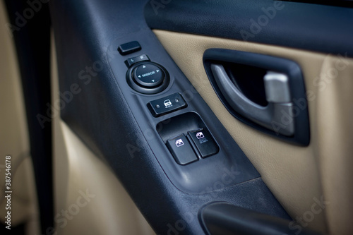 Сlose-up of the car black interior: the side door buttons: window adjustment buttons, door lock and other buttons. © Muanpare