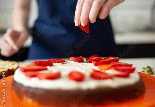 young woman decorates a birthday cake with strawberries. cake decoration.