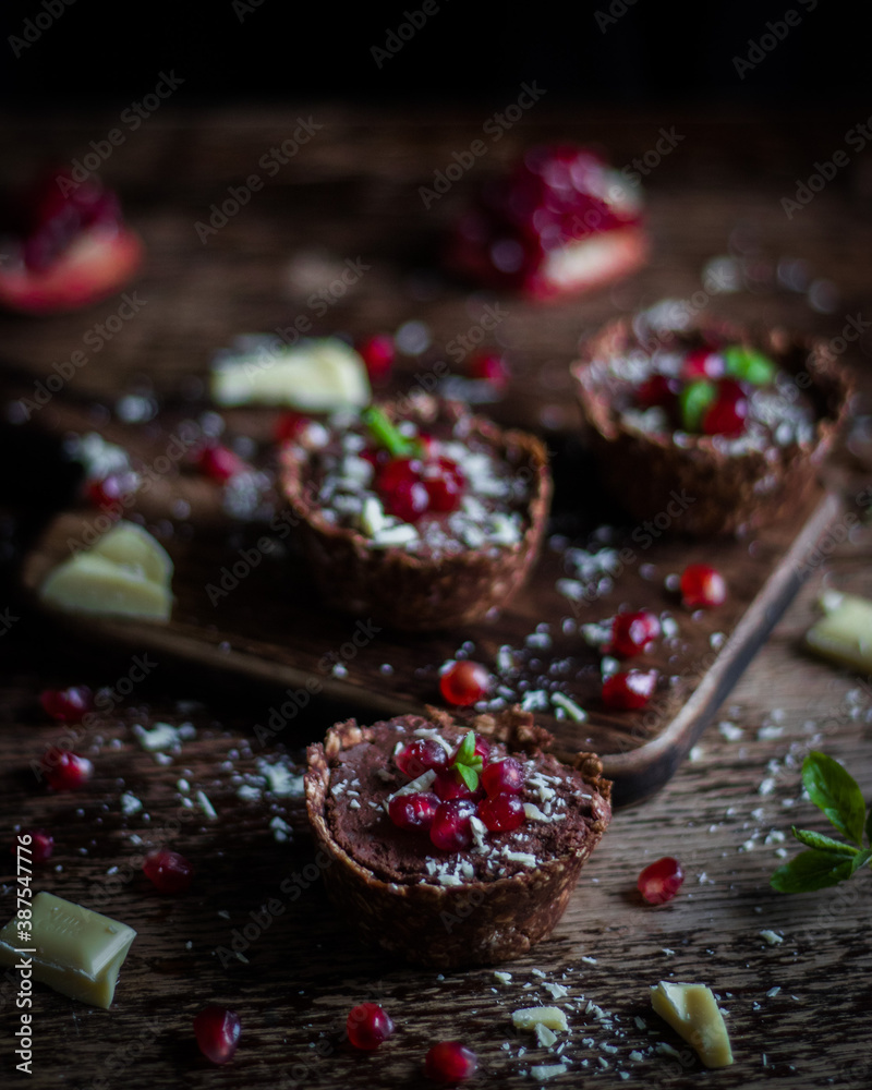 chocolate baskets with homemade nutella and garnished with pomegranate on a dark wooden background