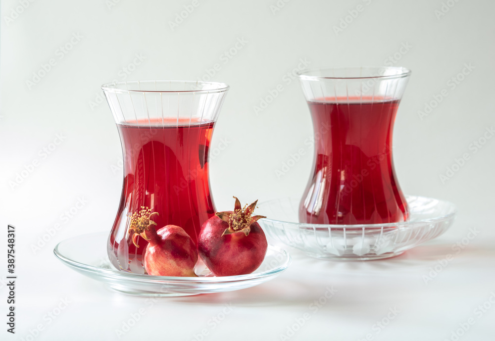 Turkish pomegranate tea in a glass cups isolated on white background, close-up. Traditional herbal tea with flowers and fruit of pomegranate in Turkey. Turkish pomegranate tea in a glass cups isolated on white background, close-up. Traditional herbal tea with flowers and fruit of pomegranate in Turkey.