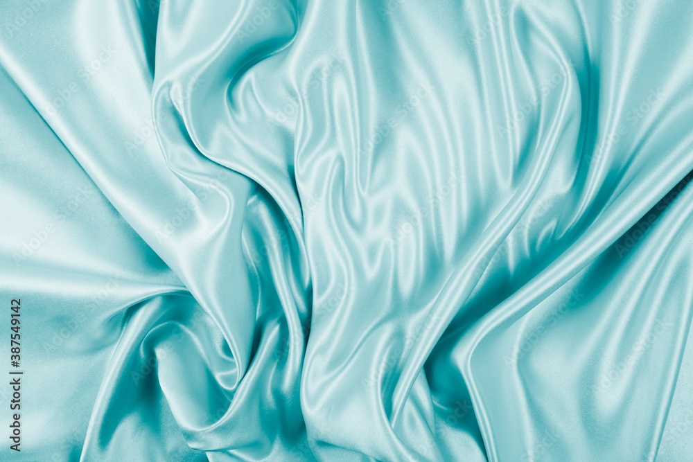 Obraz premium Photography of beautiful wavy turquoise silk satin luxury cloth fabric, abstract background design.