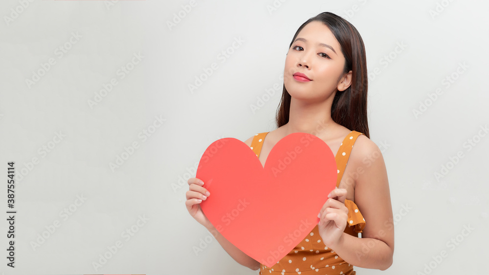 Smiling asian girl holding big red heart shape, and looking away Smiling asian girl holding big red heart shape, and looking away