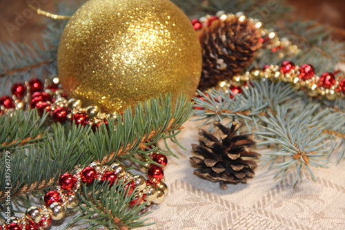 Golden ball, fir branches, cones and Christmas decorations on a gray background
