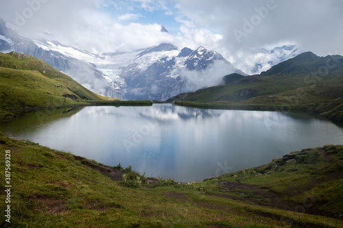 Snow and fog covered mountain reflected in a lake near First, Switzerland on a summer day.