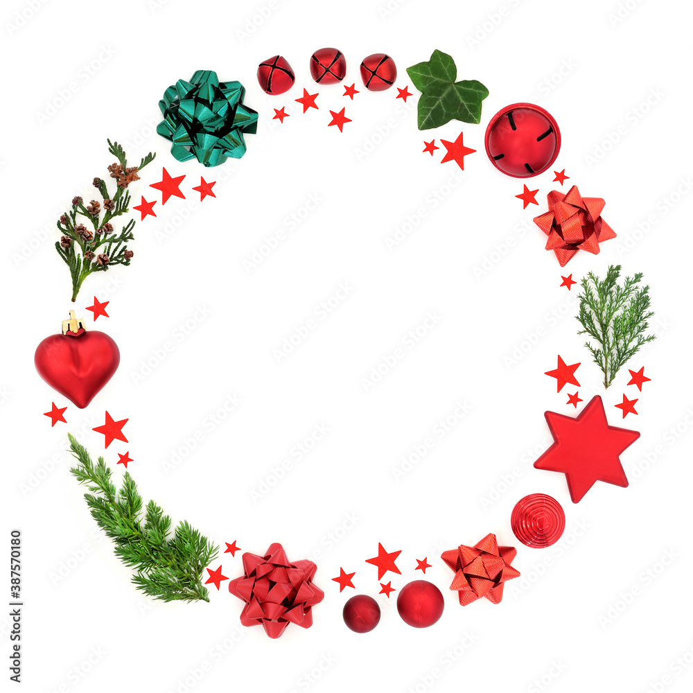Abstract Christmas wreath decoration with cedar, fir & ivy leaves with baubles, bows & red stars on white background. Festive composition for the holiday season. Flat lay, top view, copy space. Abstract Christmas wreath decoration with cedar, fir & ivy leaves with baubles, bows & red stars on white background. Festive composition for the holiday season. Flat lay, top view, copy space.