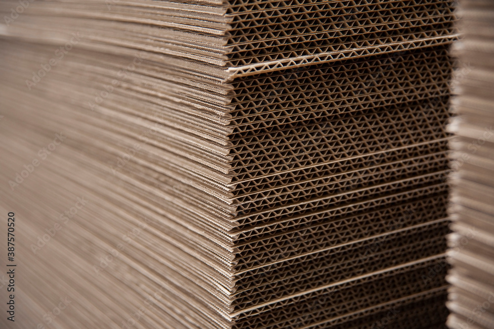 Sheets of corrugated cardboard are carefully cut and prepared for the manufacture of boxes at the printing company for various goods - obrazy, fototapety, plakaty 
