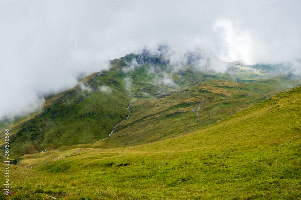 Fog covering a green hill on a summer day in the Valais Alps of Switzerland near First. 