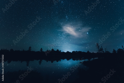 Nearly clear night skies as seen from Torrance Barrens dark sky reserve, Muskoka, Ontario, featuring stars reflecting in the lake