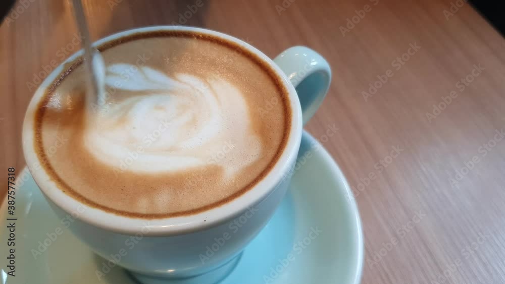 cappuccino bubbles in coffee cup spoon stirring close up cappuccino bubbles in coffee cup spoon stirring close up