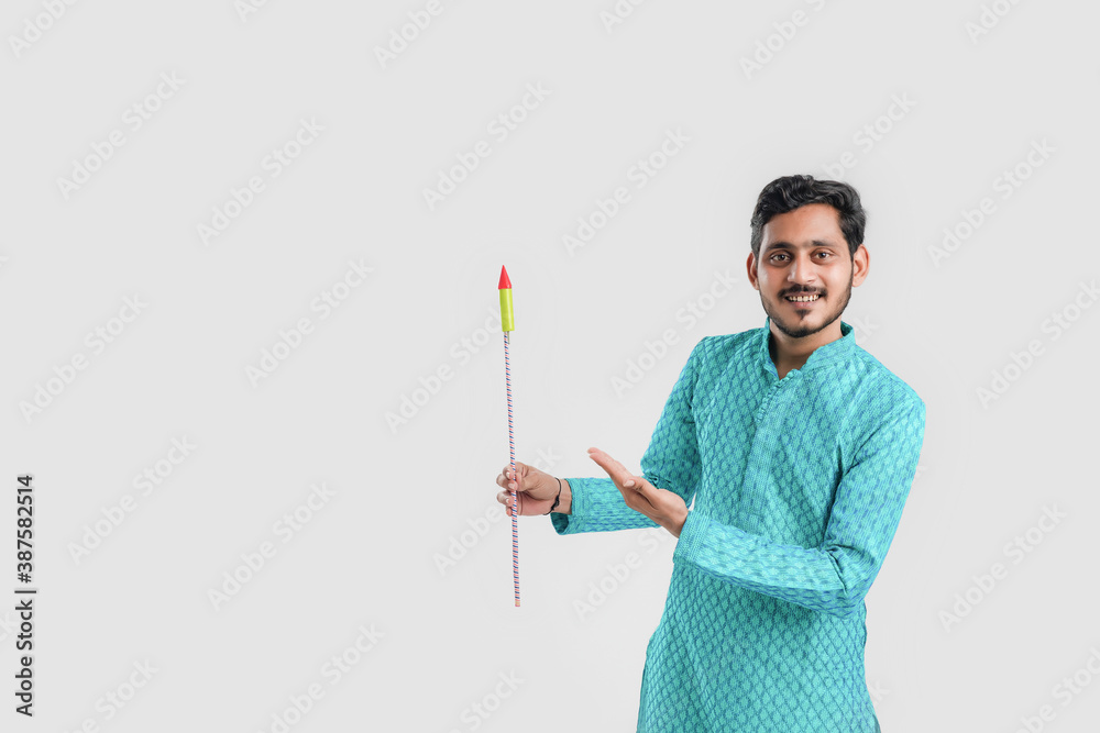Diwali festival concept, Young Indian man in ethnic wear and holding Glossy exploding Rockets in hand on white background