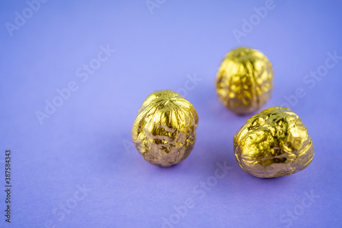Three walnuts colored in golden color on a violet background. Selective focus 