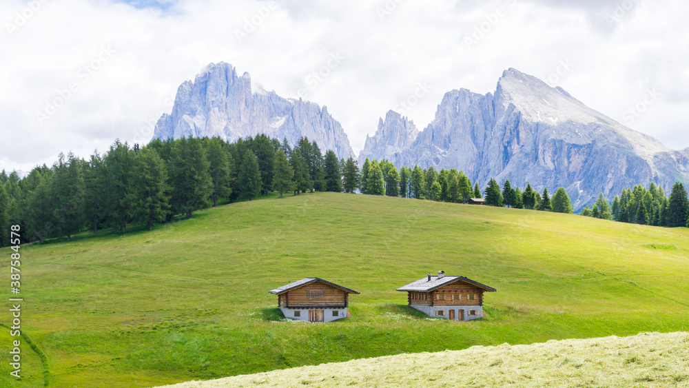 two wooden huts in a field, Alpe di Siusi or Seiser Alm, Dolomites Alps, South tyrol, Italy. 