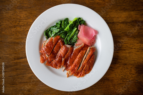 Roasted duck or peking duck and vegetables, Chinese style on wooden background.