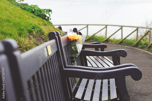 flower tribute in remembrance left on a wooden bench overlooking the sea