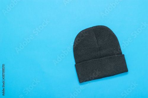 Black knitted women's hat on a blue background.