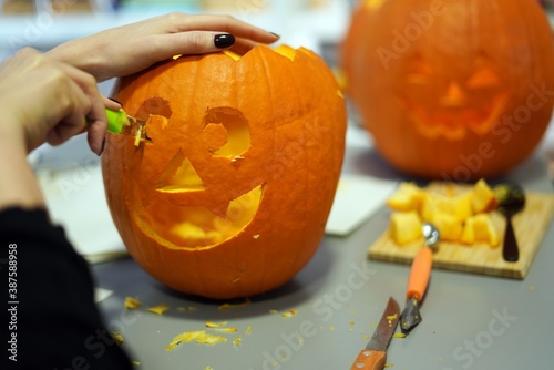 Woman carving pumpkin or jack-o-lantern at home. Halloween holiday activity concept.  