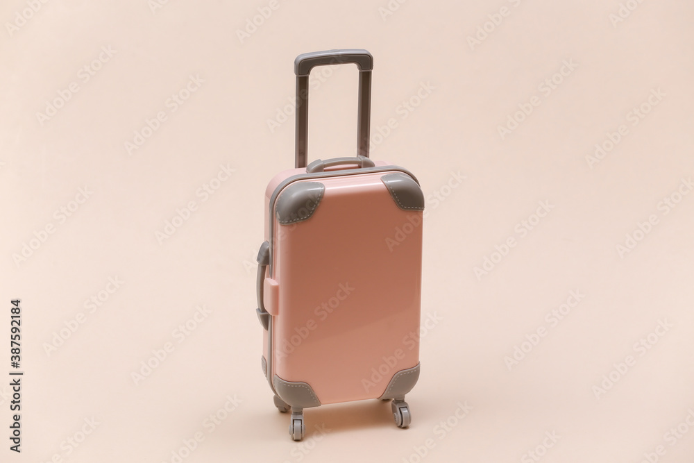 Travel or trip concept. Mini plastic travel suitcase on beige background. Minimal style Travel or trip concept. Mini plastic travel suitcase on beige background. Minimal style