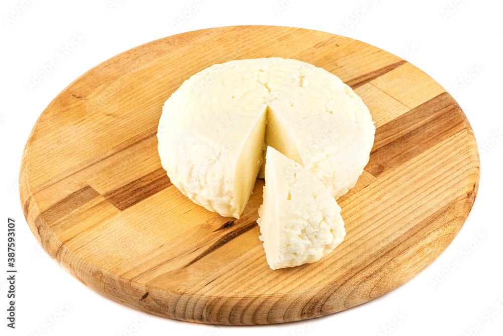 Round soft cheese with a cut triangular piece on a wooden cutting board.