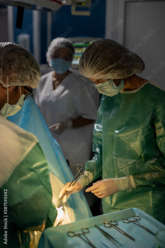 Contemporary surgeons doing operation against their assistant in operating room Contemporary surgeons doing operation against their assistant in operating room