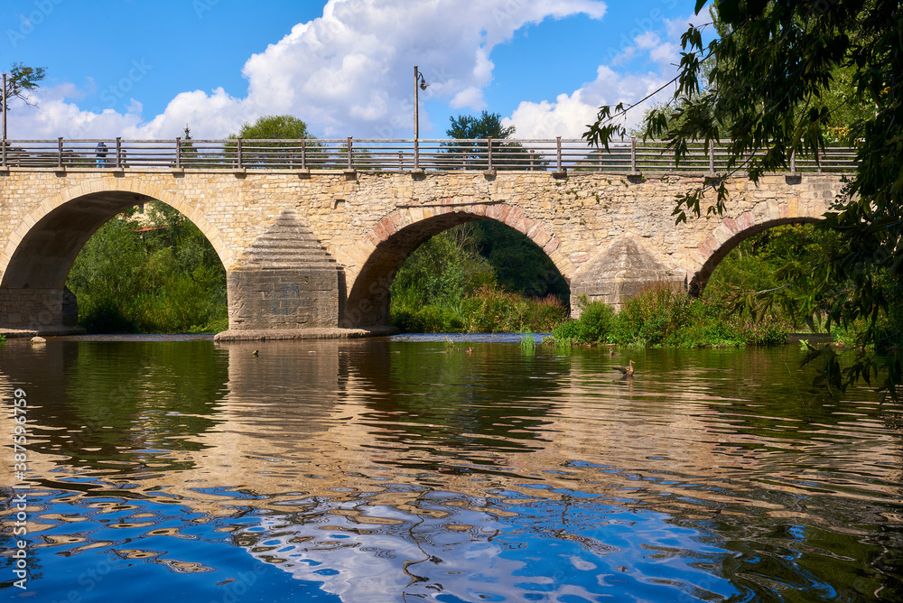 Fototapeta premium Beautiful old bridge over a calm river on a Sunny day