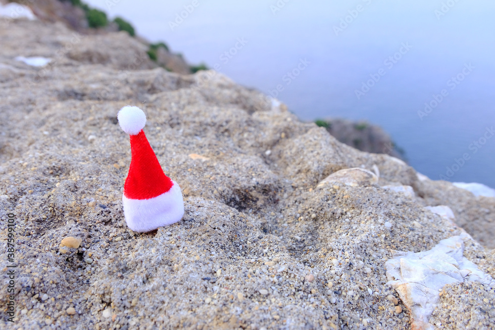 Santa Claus cap on a rock near the sea, ocean. new year celebration. The concept of a fun holiday. Holidays by the sea in the new year. 2021 quarantine, pandemic on the planet. Santa Claus cap on a rock near the sea, ocean. new year celebration. The concept of a fun holiday. Holidays by the sea in the new year. 2021 quarantine, pandemic on the planet.