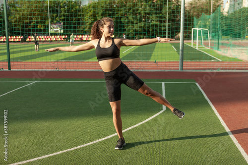 Outdoor training. Attractive sexy fitness model warms up and stretches the muscles before training © splitov27
