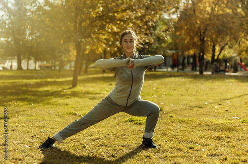 Aerobics workout outdoors. Young sport woman in sportswear is training in the autumn park.