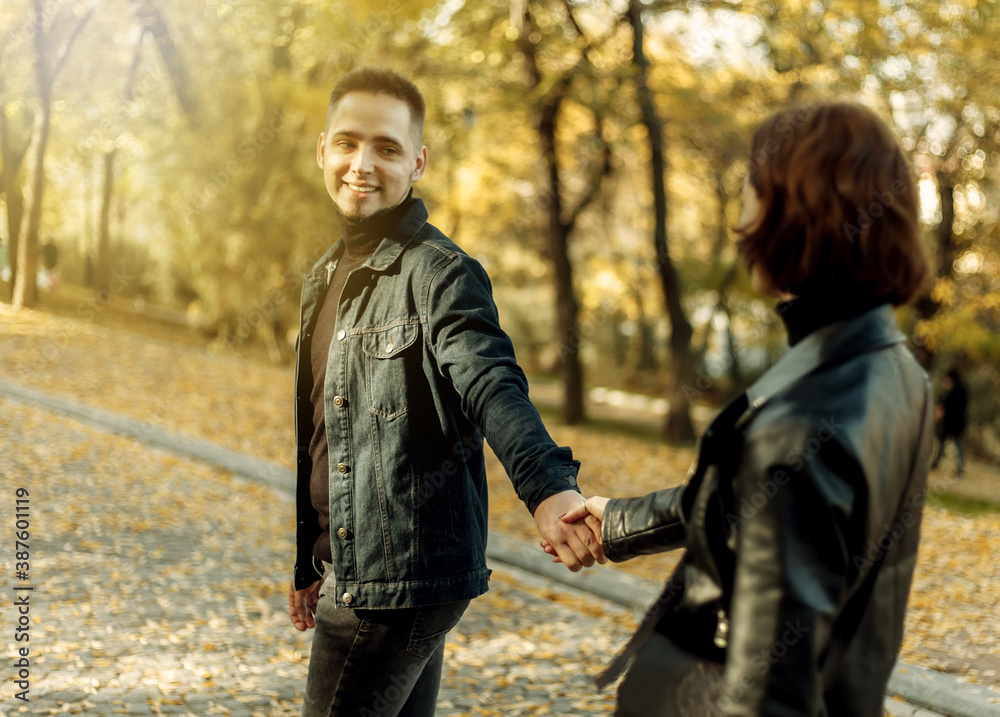 Young couple in love walking in the autumn city park holding hands. Romantic date Young couple in love walking in the autumn city park holding hands. Romantic date